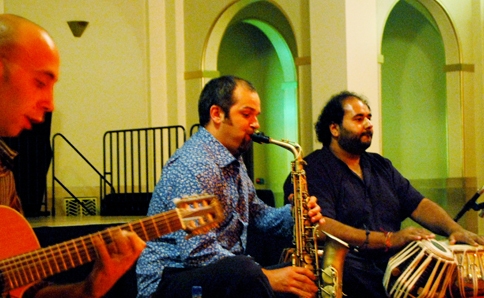 Jesse seated playing his saxophone with Giuliano Modarelli on Guitar and Bhupinder Singh Chaggar on Tabla. 