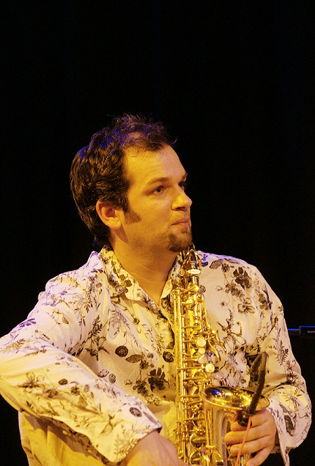 Jesse in cream indian shirt with a dark shadowed background. 