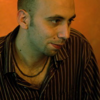 A headshot of Giuliano Modarelli in a brown italian shirt, internal, orange background. 3rd April 2013 - Steiner - A guitar and saxophone track with Giuliano Modarelli.